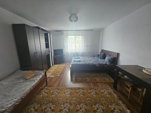 a room with two beds and a table in it at Podgoria Guesthouse- Camere de închiriat in Oradea