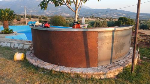 a large metal tub sitting next to a swimming pool at Κτήμα ΓΟΥΡΔΟΎΠΗ Georgιο in Lalióti
