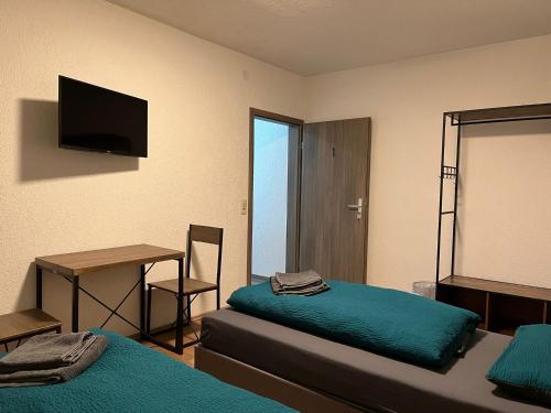 a room with two beds and a desk and a television at HausOase Zimmervermietung Gergert in Schwäbisch Hall