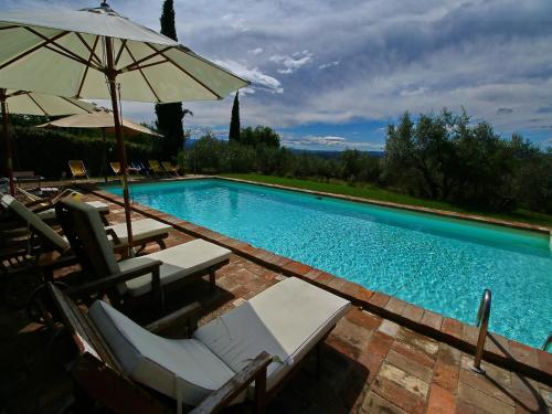 a swimming pool with chairs and an umbrella at Farmhouse in Todi with Pool & Theater Nearby in Chioano