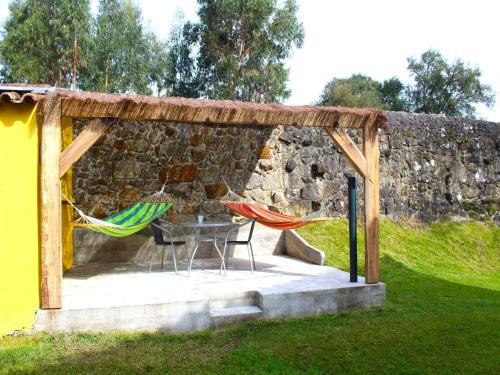 a patio with a table and chairs and a stone wall at Santa Comba Garden Cottage in Ponte de Lima
