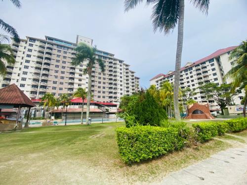a park with palm trees and a large building at Homestay FA Seaview in Port Dickson