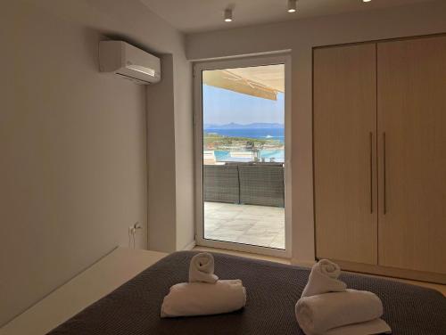 Dream View Vouliagmeni في أثينا: غرفة نوم مع منشفتين بيضاء على سرير مع نافذة