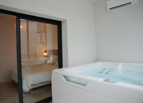 a white bathroom with a tub and a bedroom at La verrière in Avignon