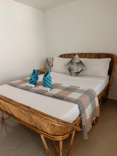 a wicker bed with two blue pillows on it at La Sirenne Inn in El Nido