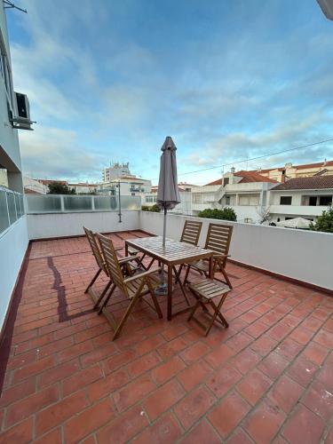 a patio with a table and chairs and an umbrella at Apartamento amplio T3 Sao Bras de Alportel in São Brás de Alportel