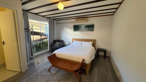 a bedroom with a bed and a chair and a window at Sunrises Kalbarri in Kalbarri