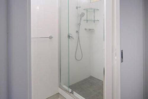 a shower stall with a glass door with a shower head at Sunrises Kalbarri in Kalbarri