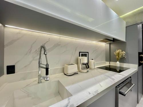 a kitchen with white marble counter tops and a sink at Top of the Alpha Duplex in Barueri