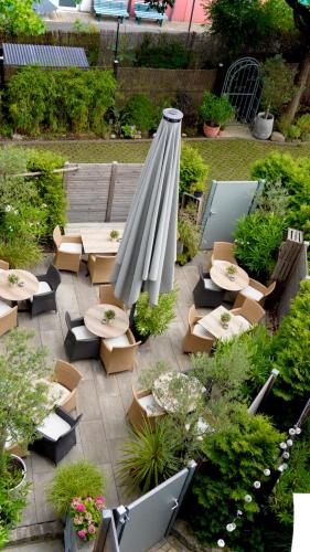 a patio with tables and chairs and a large umbrella at Hotel am Bergl in Schweinfurt