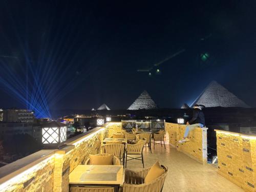 a man sitting on a ledge with tables and chairs at secret of pyramids view in Cairo