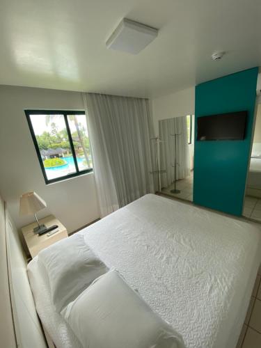a bedroom with a white bed and a window at Marulhos Resort by HomeTemp in Porto De Galinhas