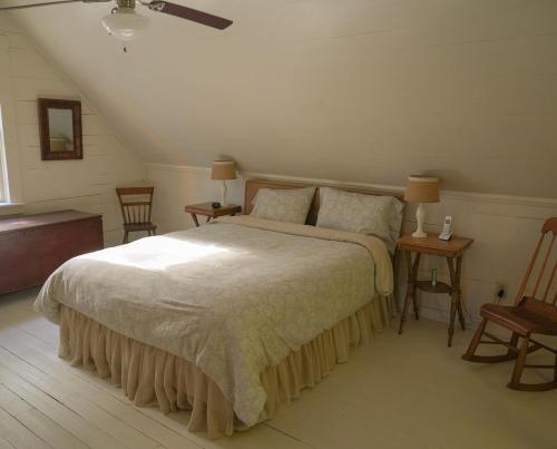 a bedroom with a large bed and two chairs at Charming 1-bedroom Waterfront Cottage in Morgan VT in Morgan