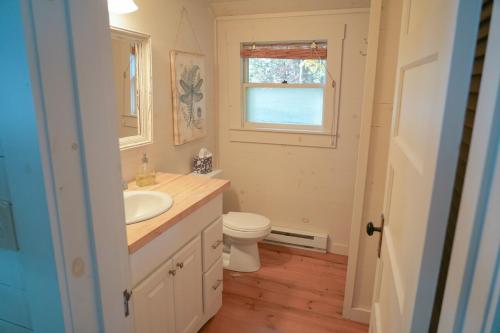 a bathroom with a sink and a toilet and a window at Charming 1-bedroom Waterfront Cottage in Morgan VT in Morgan