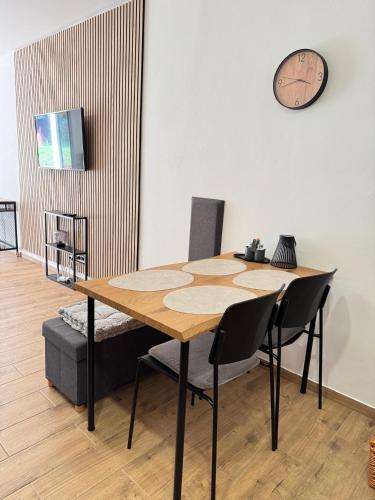 a dining room table with chairs and a clock on the wall at Apartmán Mácháč in Doksy