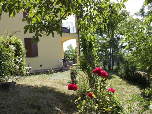 a garden with red flowers in front of a building at Rural Retreat in Sassoleone in Sassoleone