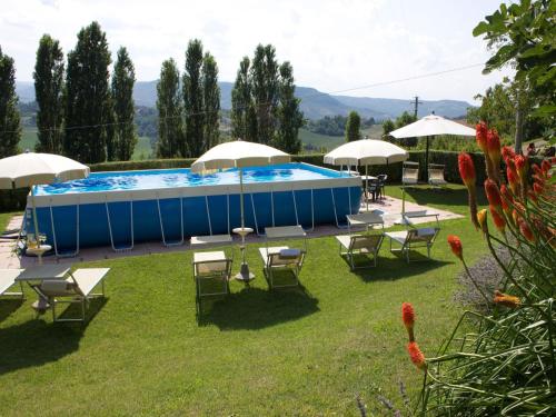 a pool with a bunch of chairs and umbrellas at Rural Retreat in Sassoleone in Sassoleone