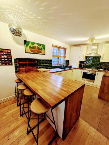a kitchen with a large wooden table and stools at Detached House with Gated Parking in Whalley Range, Near Manchester City Centre in Manchester