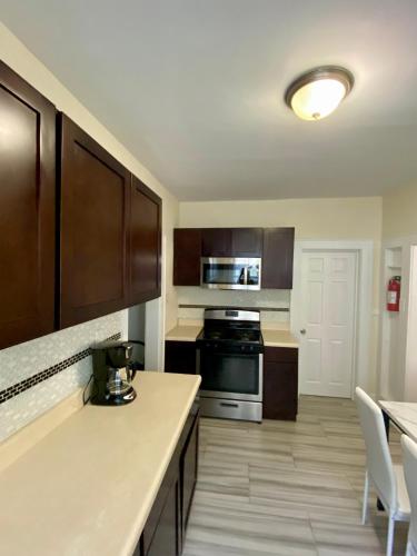 a kitchen with wooden cabinets and a stove top oven at Tropical Oasis - Room 3 in Irvington