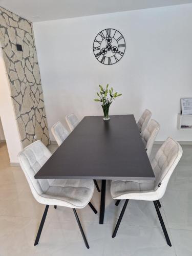 a dining room with a black table and white chairs at Apartman Mista in Solin