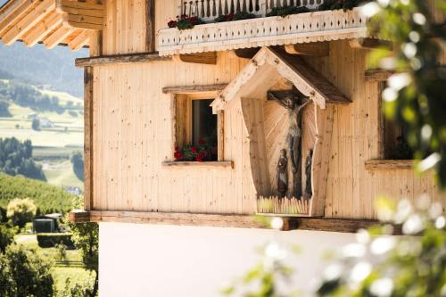 a wooden bird house with a statue in the window at Huberhof in Fiè