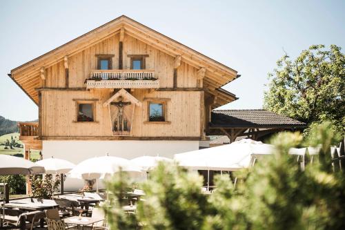 a wooden building with a balcony and tables and umbrellas at Huberhof in Fiè