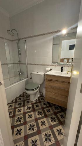 a bathroom with a toilet and a sink and a mirror at Hostal Playa Hidalgo in Rota