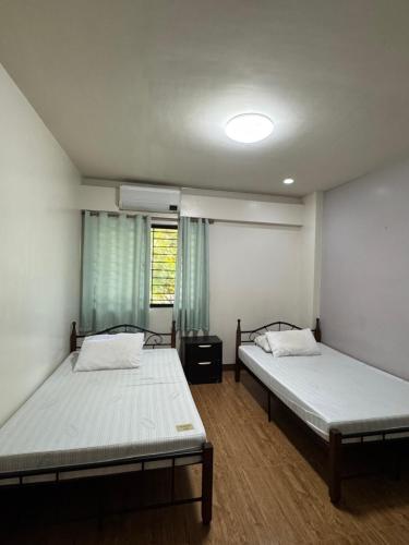two beds in a room with two windows at C7 Hotel with beach front access in Iloilo City