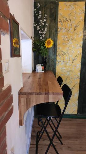 a wooden table with two chairs and a vase of flowers at Rustichello G&P Tuscany in Lorenzana