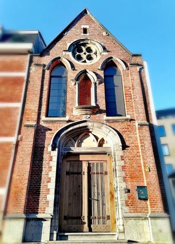 a tall brick church with a door and a window at Unique renovated chapel in Temse