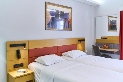 a hotel room with two beds and a desk at Hotel Erika in Alexandroupoli