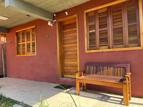 a wooden bench sitting on the side of a house at Ótima casa de praia a 2 quadras do mar in Tramandaí