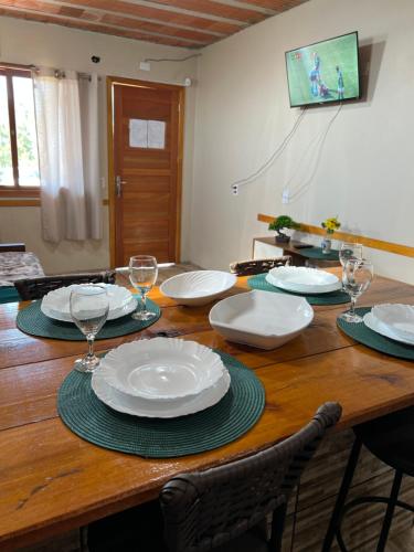 a wooden table with plates and wine glasses on it at Ótima casa de praia a 2 quadras do mar in Tramandaí
