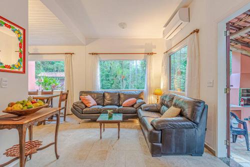 ein Wohnzimmer mit 2 Ledersofas und einem Tisch in der Unterkunft Camburi 5 quartos com piscina natural in Camburi