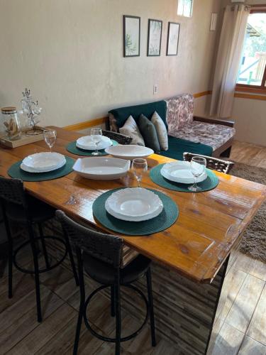 a wooden table with plates and wine glasses on it at Ótima casa de praia a 2 quadras do mar in Tramandaí