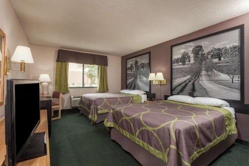 a hotel room with two beds and a flat screen tv at Super 8 by Wyndham Carrollton in Carrollton