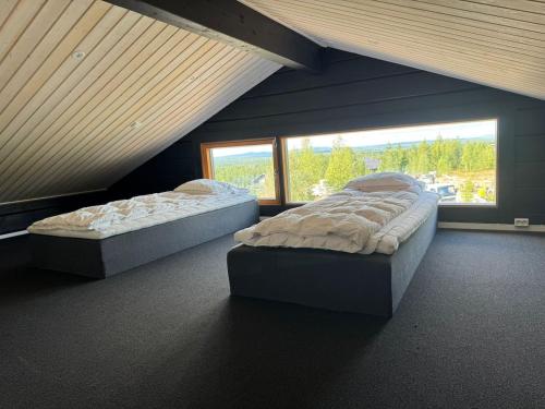 two beds in a room with a large window at Villa Ruka - Rising Sun with 3 bedrooms, loft, sauna and balcony with a view in Ruka