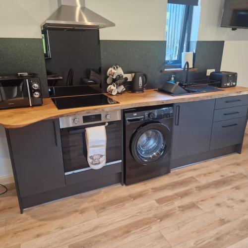a kitchen with a stove and a washing machine at Temuka Lodge in Glenurguhart