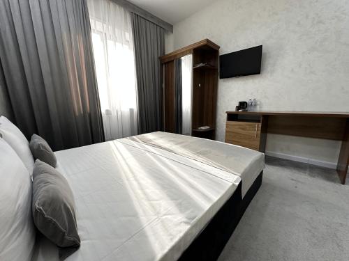 a bedroom with a bed and a desk and a television at Grand Zamin Hotel in Tashkent
