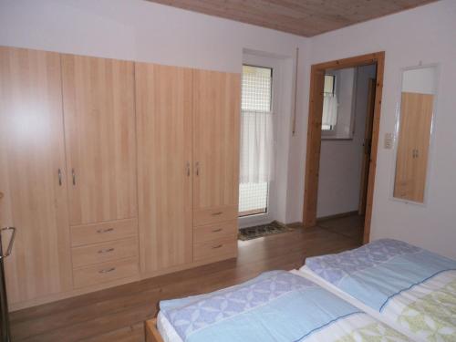 une chambre avec des armoires en bois et un lit dedans dans l'établissement Ferienwohnung mit Entspannungserlebnis im Garten mit Terrasse, à Wildpoldsried