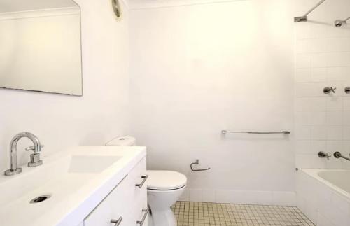 een witte badkamer met een wastafel en een toilet bij FlexiRoom on Hereford in Sydney