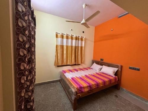 a bedroom with a bed with an orange wall at M S , Homes in Tiruvannāmalai