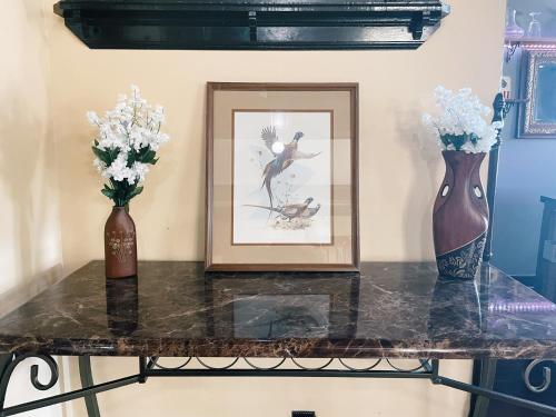 two vases and a picture on a table with flowers at Victorian Home in Original Grandeur Downtown in Kokomo