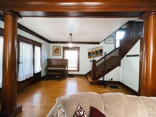a living room with a staircase and a piano at Victorian Home in Original Grandeur Downtown in Kokomo