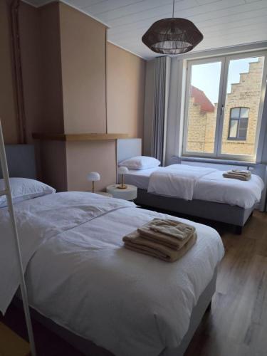 two beds in a hotel room with towels on them at vakantiewoning 't Rijhuys in Diksmuide