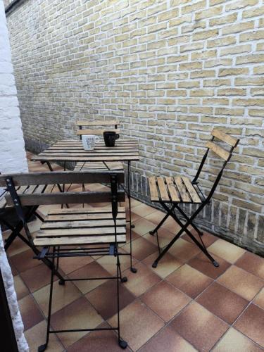 a table and two chairs next to a brick wall at vakantiewoning 't Rijhuys in Diksmuide