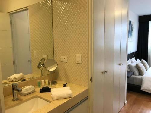 a bathroom with a sink and a mirror and a bed at Cozy, Elegant & Comfortable Apartment in Lima in Lima