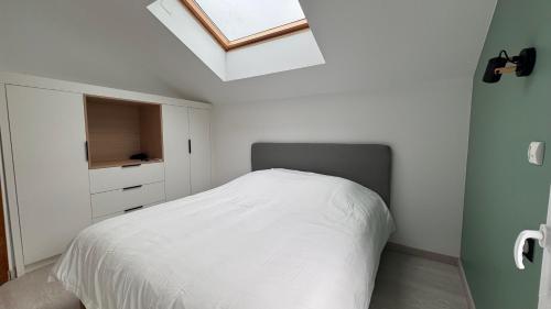 a bedroom with a white bed and a skylight at LEPTILOFT BAYEUX Centre in Bayeux