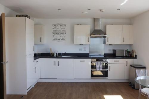 a kitchen with white cabinets and black counter tops at Top-Floor Penthouse with Panoramic Views in Romford