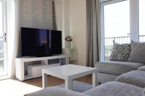 a living room with a tv and a couch and a table at Top-Floor Penthouse with Panoramic Views in Romford